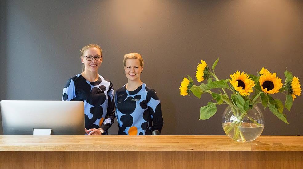 Kaksi iloista vastaanottovirkailijaa Hotel F6 -hotellin aulassa, Helsingissä, Suomessa